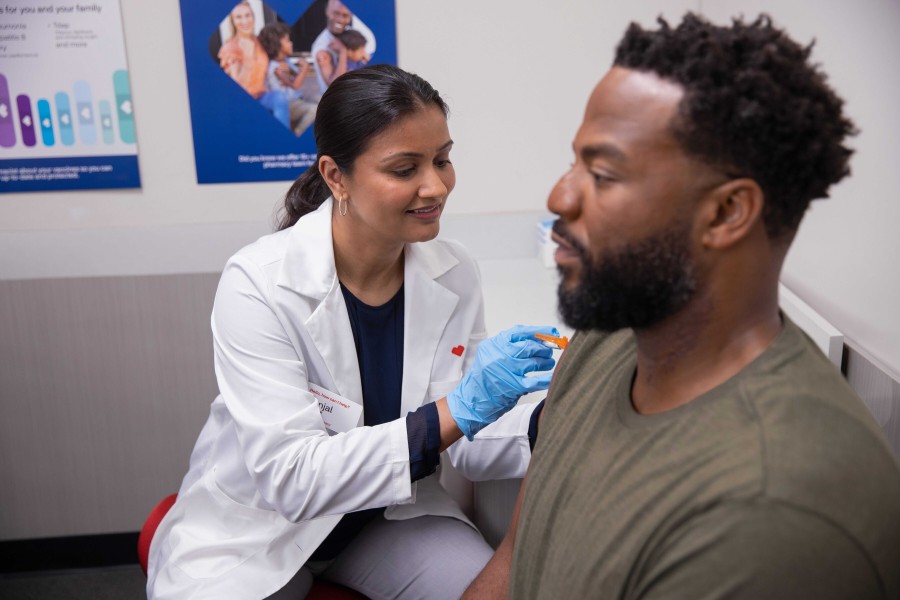 CVS pharmacist vaccinating male patient.